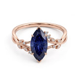 Deep-blue marquise gemstone ring with white-metal split shoulders, sparkling leaf-shaped settings and scattered round accents