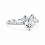 A silver-tone cluster ring featuring a large round center diamond flanked by two smaller round diamonds, with a pavé band set with additional small diamonds, shown on a clean white background.