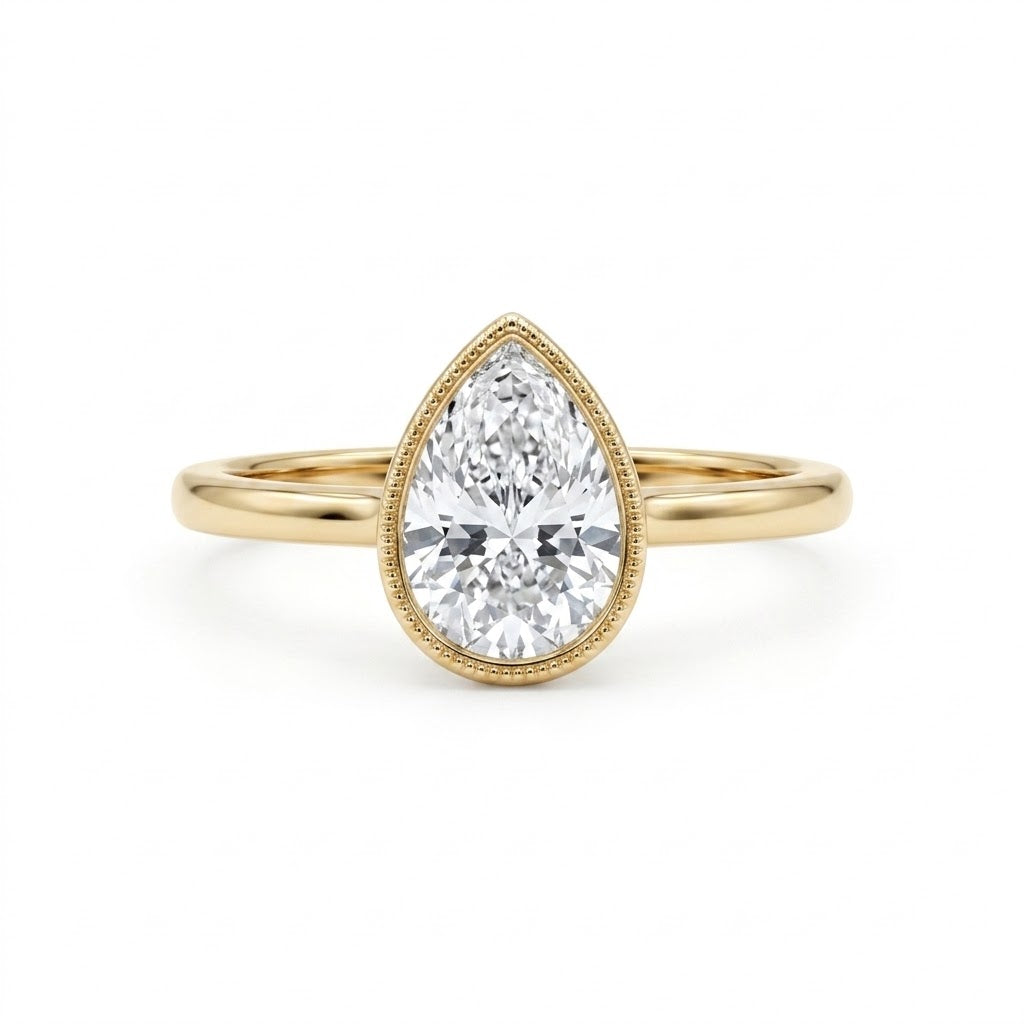 Pear-cut lab-grown diamond bezel solitaire engagement ring with fine milgrain detailing and a polished yellow-gold band.