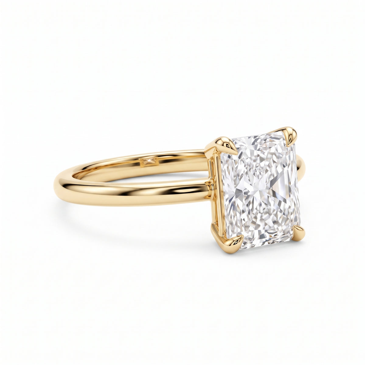 Elongated radiant-cut lab-grown diamond solitaire engagement ring with four prongs and a polished yellow-gold band.