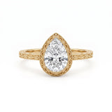 Vintage pear-cut lab-grown diamond bezel engagement ring with milgrain detailing and an engraved yellow-gold filigree band.