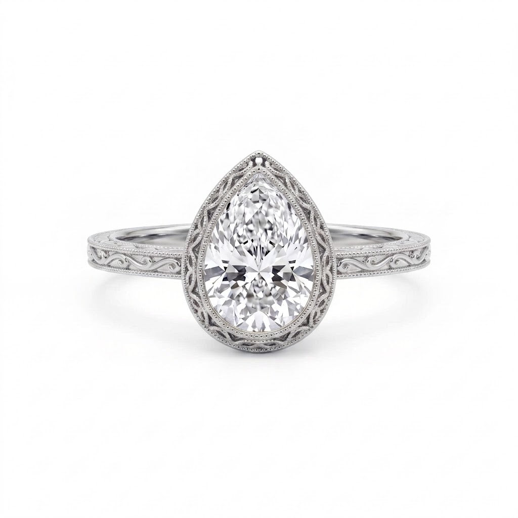 Vintage pear-cut lab-grown diamond bezel engagement ring with milgrain detailing and an engraved yellow-gold filigree band.
