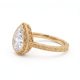 Vintage pear-cut lab-grown diamond bezel engagement ring with milgrain detailing and an engraved yellow-gold filigree band.