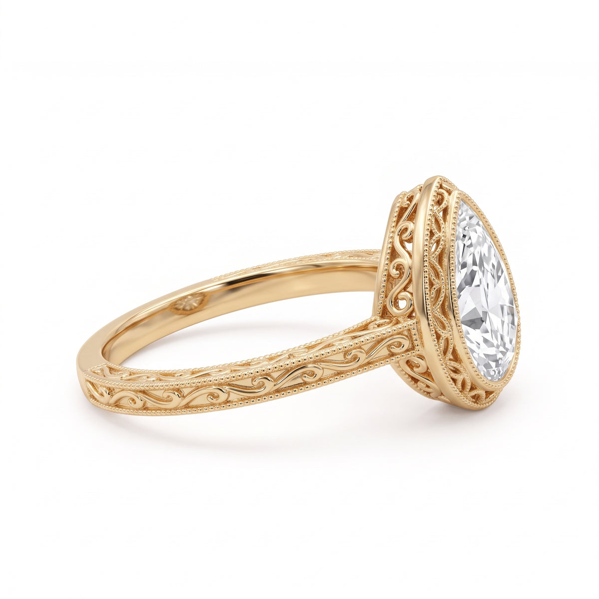 Vintage pear-cut lab-grown diamond bezel engagement ring with milgrain detailing and an engraved yellow-gold filigree band.