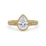 Vintage pear-cut lab-grown diamond bezel engagement ring with milgrain, scroll filigree and round diamond accents on a yellow-gold band.