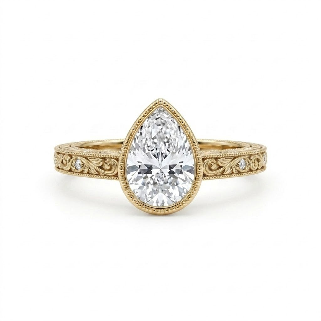 Vintage pear-cut lab-grown diamond bezel engagement ring with milgrain, scroll filigree and round diamond accents on a yellow-gold band.