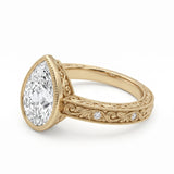 Vintage pear-cut lab-grown diamond bezel engagement ring with milgrain, scroll filigree and round diamond accents on a yellow-gold band.