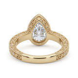 Vintage pear-cut lab-grown diamond bezel engagement ring with milgrain, scroll filigree and round diamond accents on a yellow-gold band.