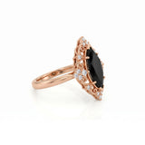Black marquise gemstone ring with ornate white-metal scrollwork, clear round accent clusters and a polished band