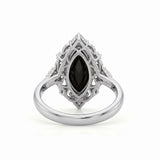 Black marquise gemstone ring with ornate white-metal scrollwork, clear round accent clusters and a polished band