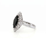 Black marquise gemstone ring with ornate white-metal scrollwork, clear round accent clusters and a polished band