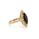 Black marquise gemstone ring with ornate white-metal scrollwork, clear round accent clusters and a polished band