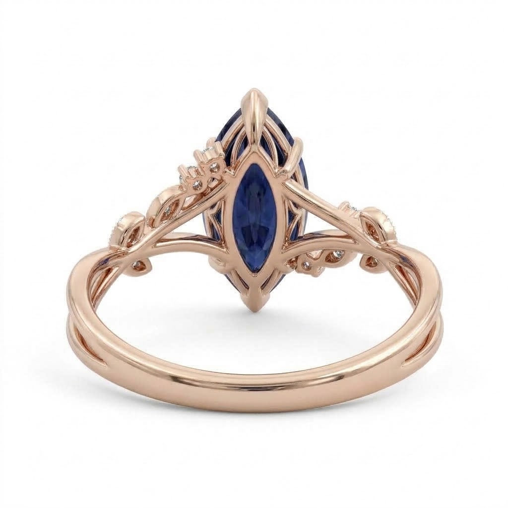Deep-blue marquise gemstone ring with white-metal split shoulders, sparkling leaf-shaped settings and scattered round accents