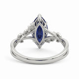 Deep-blue marquise gemstone ring with white-metal split shoulders, sparkling leaf-shaped settings and scattered round accents