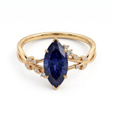 Deep-blue marquise gemstone ring with white-metal split shoulders, sparkling leaf-shaped settings and scattered round accents