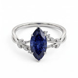 Deep-blue marquise gemstone ring with white-metal split shoulders, sparkling leaf-shaped settings and scattered round accents