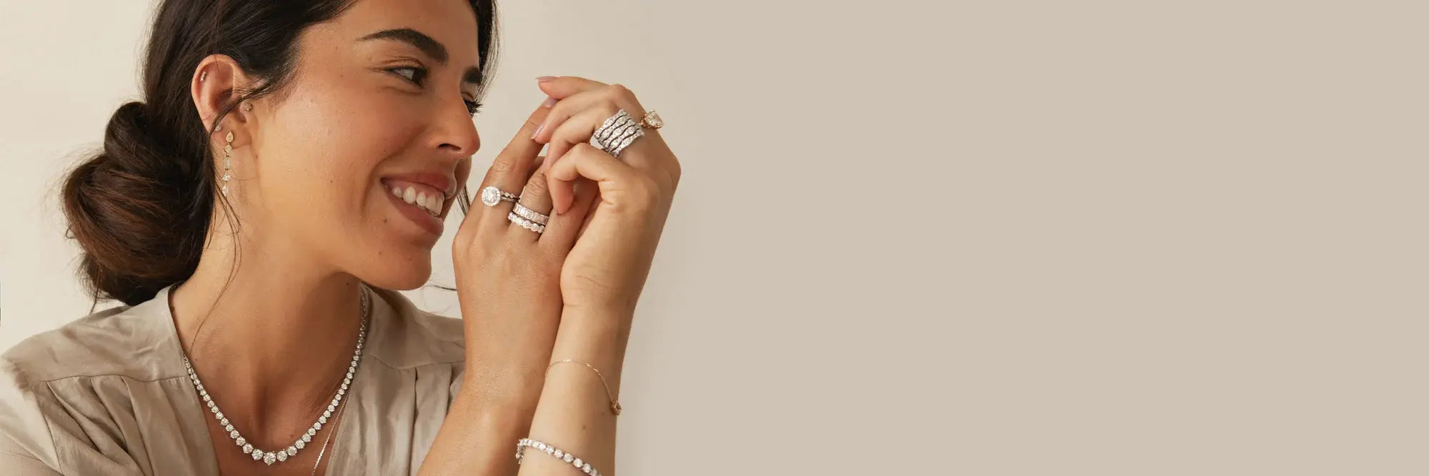 Woman wearing diamond stacking rings, tennis bracelet, diamond tennis necklace, and drop earrings