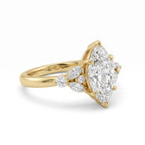 A yellow gold ring featuring a marquise-cut diamond center stone with smaller round and marquise diamonds on the shoulders, set against a clean white background.