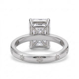 Radiant-cut solitaire engagement ring with four claw prongs and daisy flower engravings on a polished white-metal band