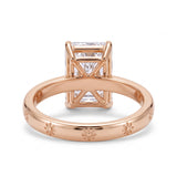 Radiant-cut solitaire engagement ring with four claw prongs and daisy flower engravings on a polished white-metal band