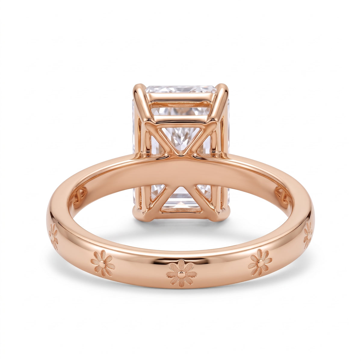 Radiant-cut solitaire engagement ring with four claw prongs and daisy flower engravings on a polished white-metal band