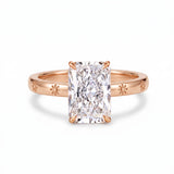 Radiant-cut solitaire engagement ring with four claw prongs and daisy flower engravings on a polished white-metal band