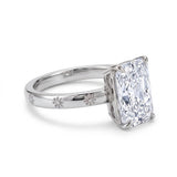 Radiant-cut solitaire engagement ring with four claw prongs and daisy flower engravings on a polished white-metal band