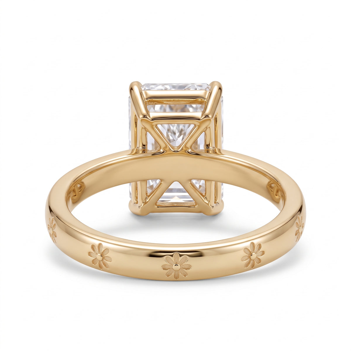 Radiant-cut solitaire engagement ring with four claw prongs and daisy flower engravings on a polished white-metal band