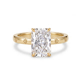Radiant-cut solitaire engagement ring with four claw prongs and daisy flower engravings on a polished white-metal band