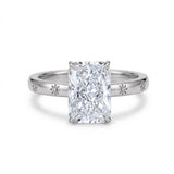 Radiant-cut solitaire engagement ring with four claw prongs and daisy flower engravings on a polished white-metal band