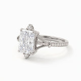Radiant-cut engagement ring with pear-shaped accents above and below the center stone, pavé diamonds and polished white-metal split shoulders