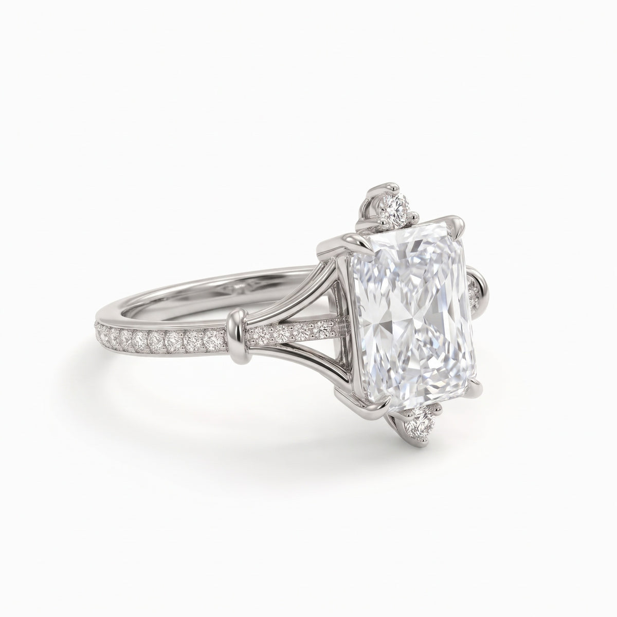 Radiant-cut engagement ring with pear-shaped accents above and below the center stone, pavé diamonds and polished white-metal split shoulders