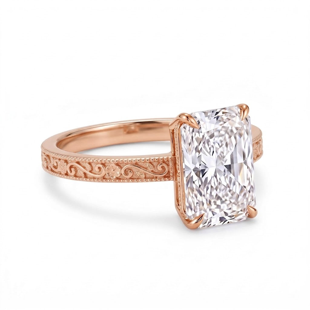Radiant-cut solitaire engagement ring with four claw prongs, floral scroll engravings and milgrain borders on a white-metal band
