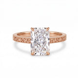 Radiant-cut solitaire engagement ring with four claw prongs, floral scroll engravings and milgrain borders on a white-metal band