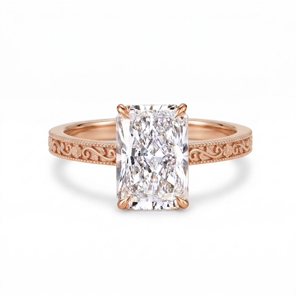 Radiant-cut solitaire engagement ring with four claw prongs, floral scroll engravings and milgrain borders on a white-metal band