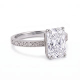 Radiant-cut solitaire engagement ring with four claw prongs, floral scroll engravings and milgrain borders on a white-metal band