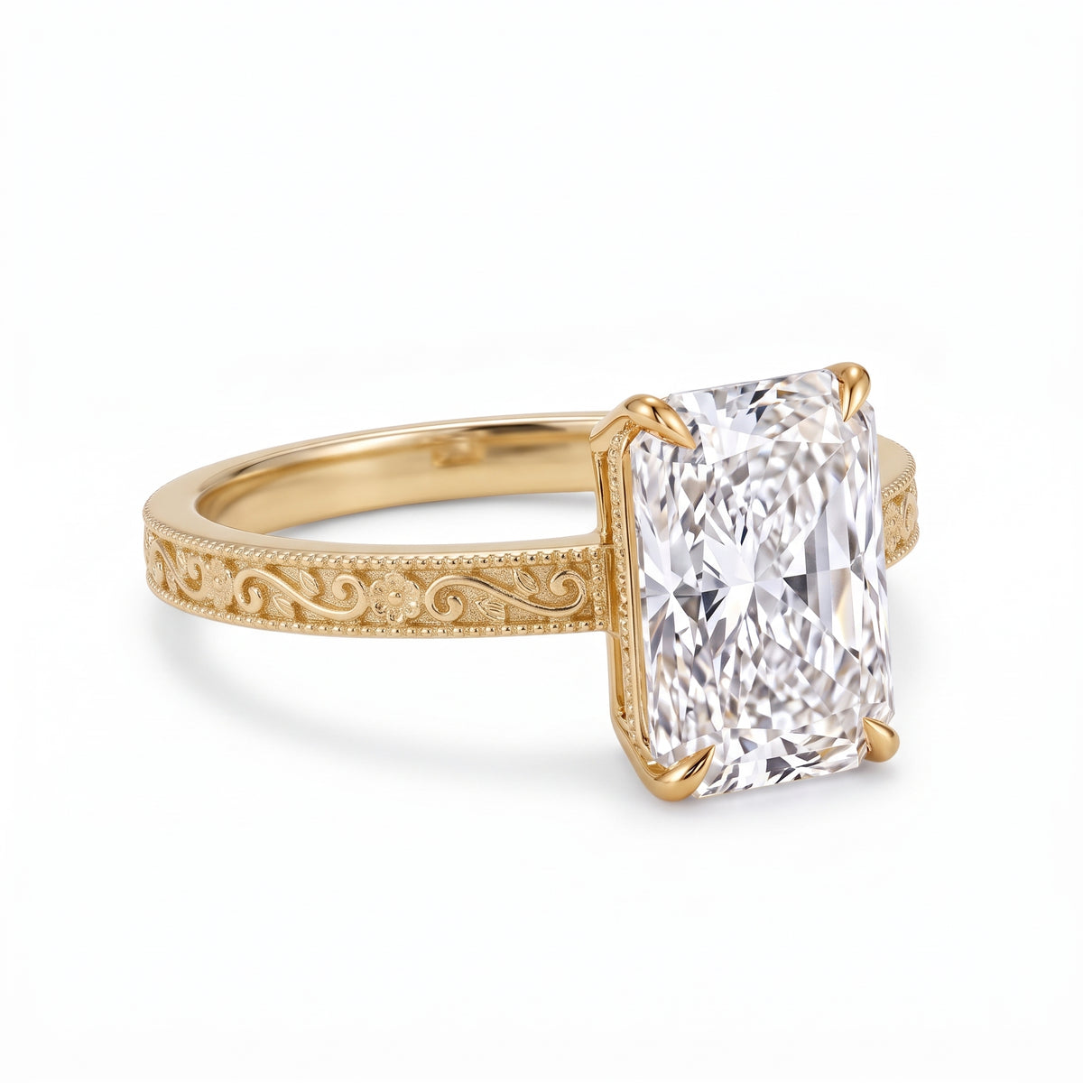 Radiant-cut solitaire engagement ring with four claw prongs, floral scroll engravings and milgrain borders on a white-metal band