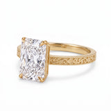 Radiant-cut solitaire engagement ring with four claw prongs, floral scroll engravings and milgrain borders on a white-metal band
