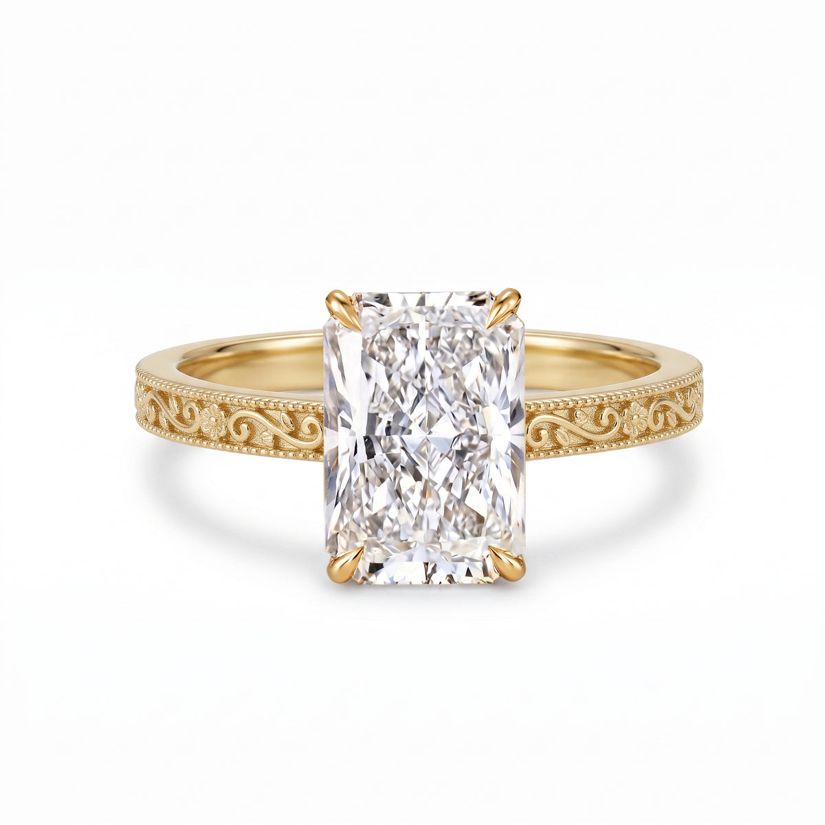 Radiant-cut solitaire engagement ring with four claw prongs, floral scroll engravings and milgrain borders on a white-metal band